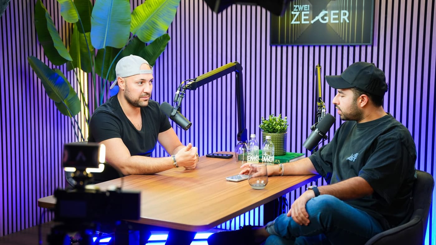 Zwei Personen sprechen an einem Podcast-Tisch in Mikrofone